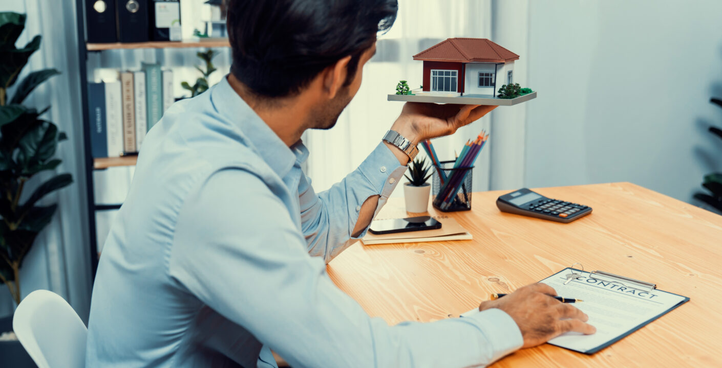 man sits desk holding house model jpg
