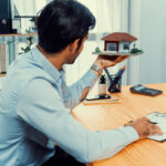 man sits desk holding house model jpg